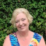 Woman smiling, short blonde hair and multicolored dress on; Dialectical Behavior Therapy